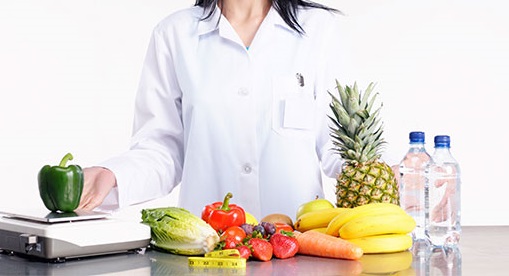 Dietitian standing next to a table full of healthy foods, fruits and vegetables.