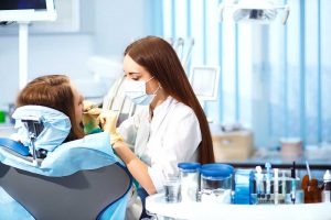 Dental Hygienist work with the patient, cleaning their gums. 