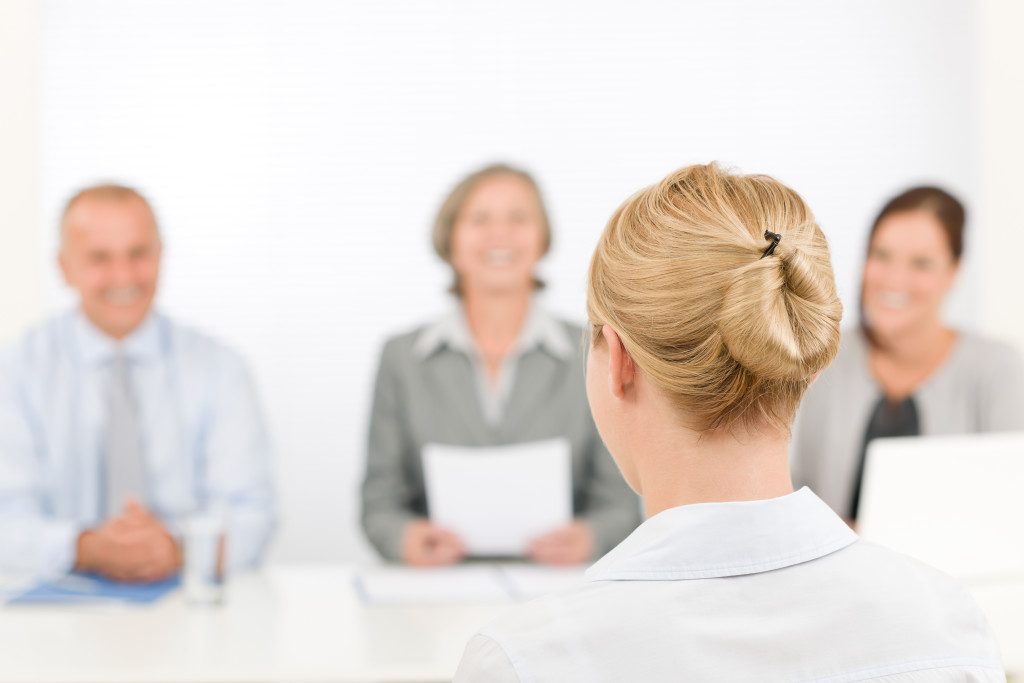 A scene from an interview - blonde woman answers questions of two mature hiring managers.