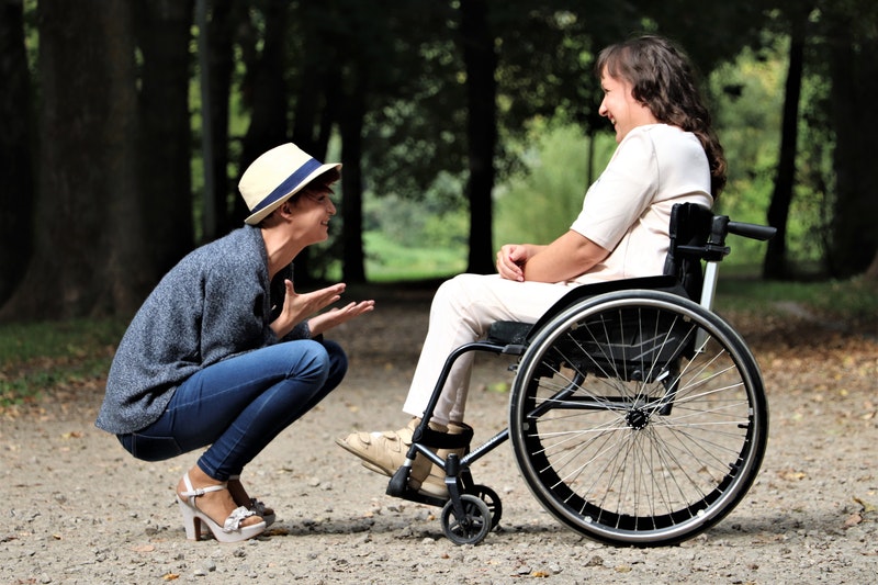 young direct support worker helps a female on wheelchair to socialize